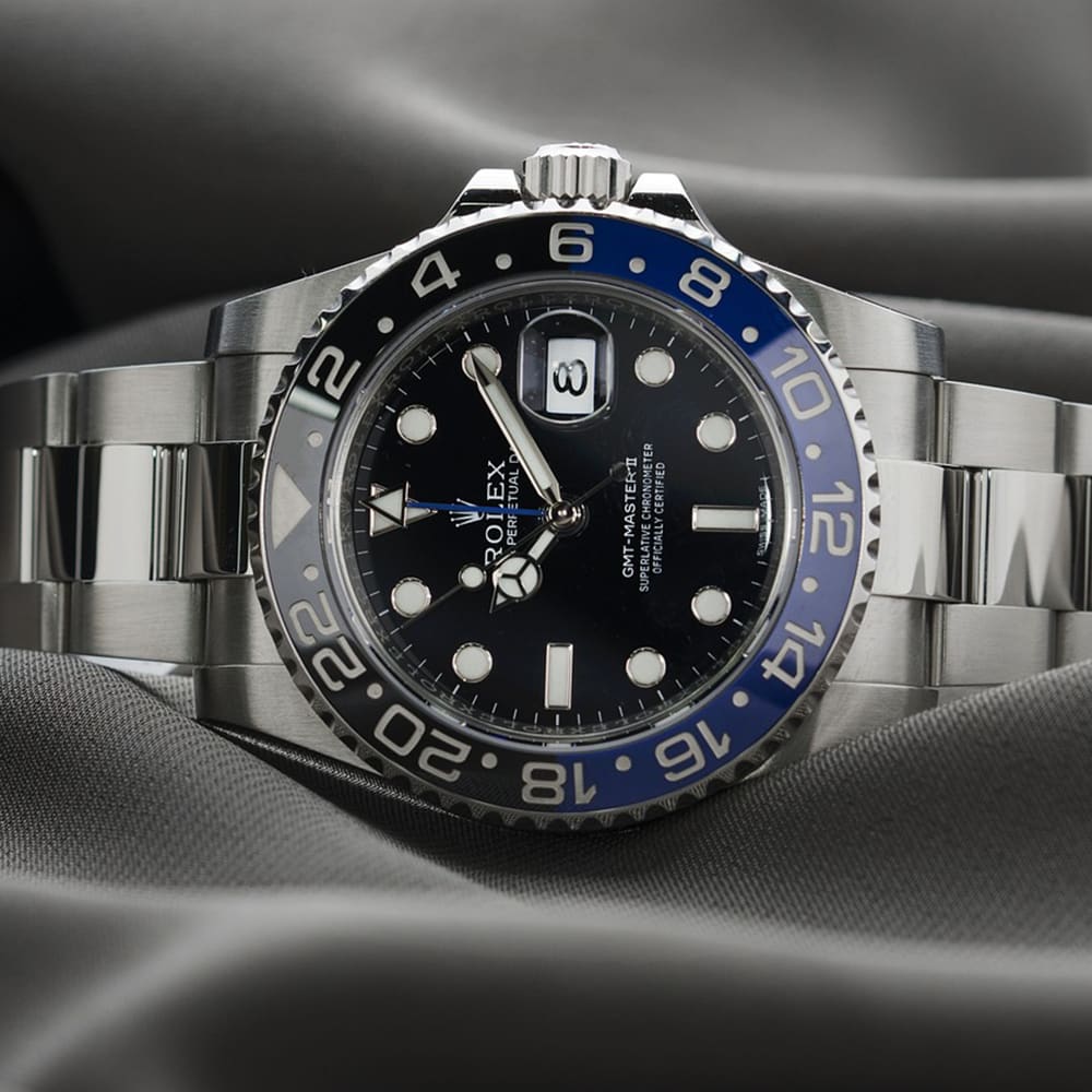 Rolex GMT-Master II with a black and blue Batman bezel and stainless steel Oyster bracelet resting on grey silk