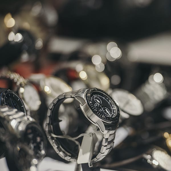 Luxury watches displayed on a stand, with a stainless steel chronograph in focus among the collection