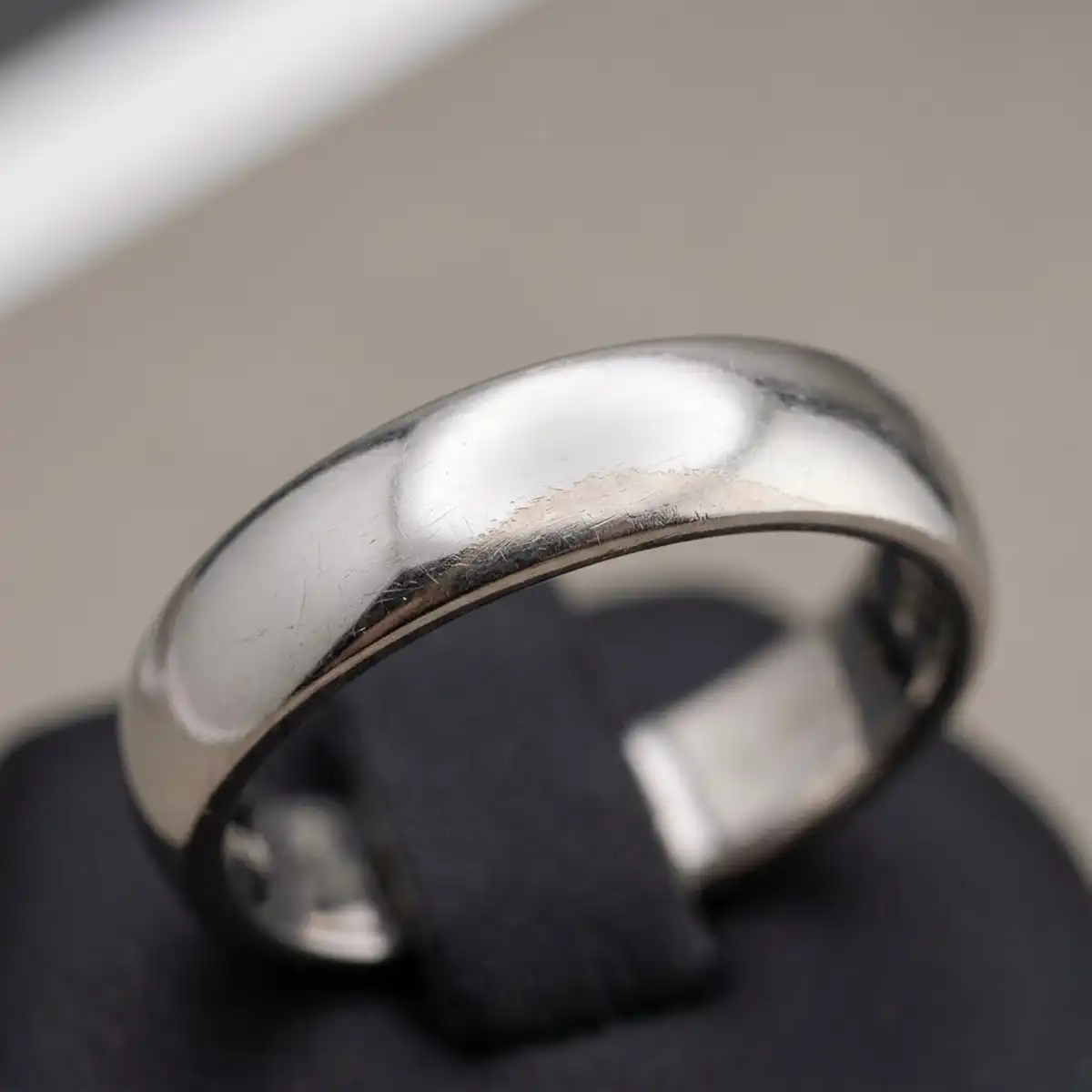 White gold ring placed beside a 950 platinum ring on a jeweller's bench, illustrating the choice between rhodium plating on white gold and naturally white platinum